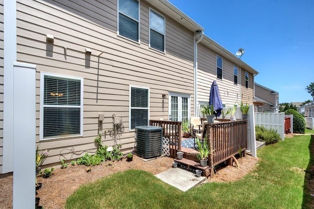 back of property with a lawn, a wooden deck, and central AC unit