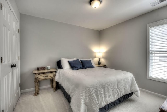 bedroom featuring baseboards, visible vents, a closet, and light colored carpet