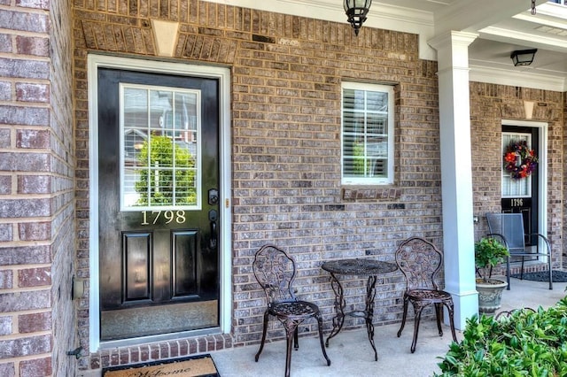 doorway to property with a porch and brick siding