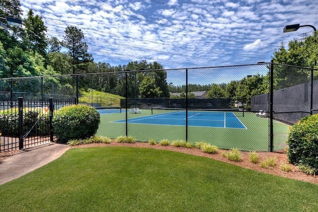 view of sport court with fence and a lawn