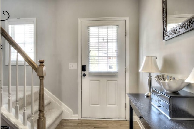 doorway with stairs, baseboards, and wood finished floors