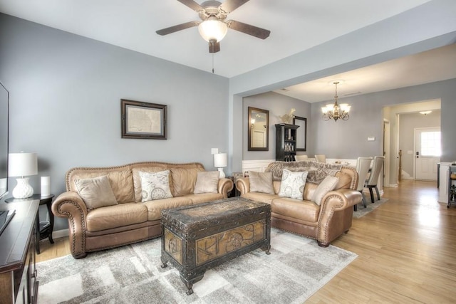 living room featuring light wood-type flooring and ceiling fan with notable chandelier