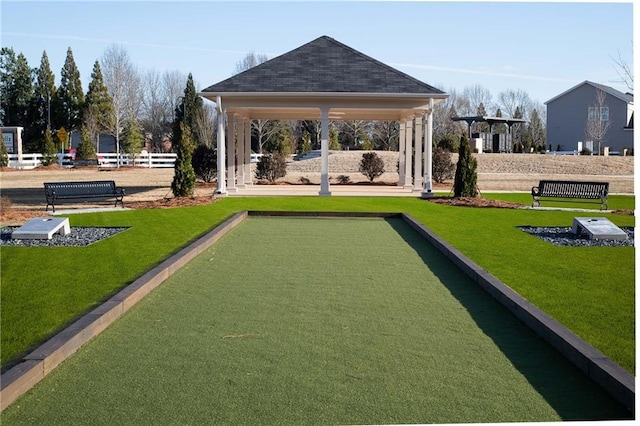 view of community with a gazebo, a lawn, and fence