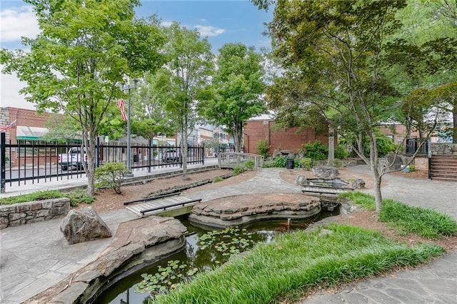 view of property's community with a small pond and fence