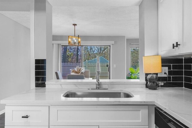 kitchen with white cabinetry, backsplash, an inviting chandelier, stainless steel appliances, and light wood-type flooring