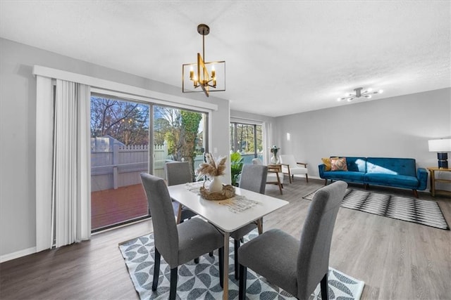 dining space with wood-type flooring, a textured ceiling, and an inviting chandelier