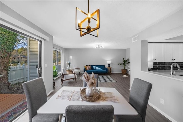 dining area featuring dark hardwood / wood-style flooring, sink, and a notable chandelier