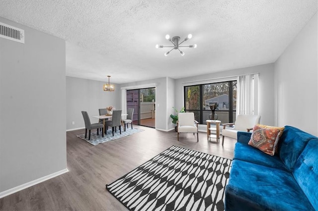 living room with a notable chandelier, hardwood / wood-style flooring, and a textured ceiling