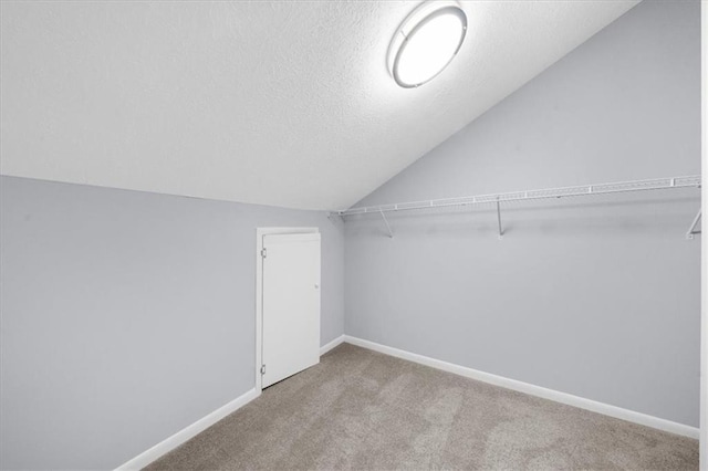 spacious closet featuring lofted ceiling and light colored carpet