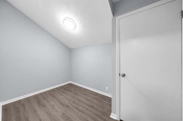 bonus room featuring wood-type flooring, lofted ceiling, and a textured ceiling