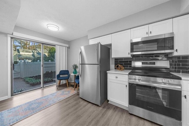 kitchen with light stone counters, tasteful backsplash, white cabinets, and appliances with stainless steel finishes