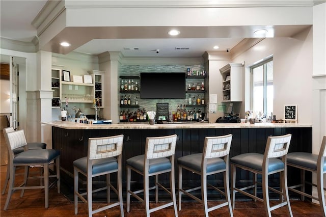 bar featuring ornamental molding, dark wood-type flooring, and backsplash