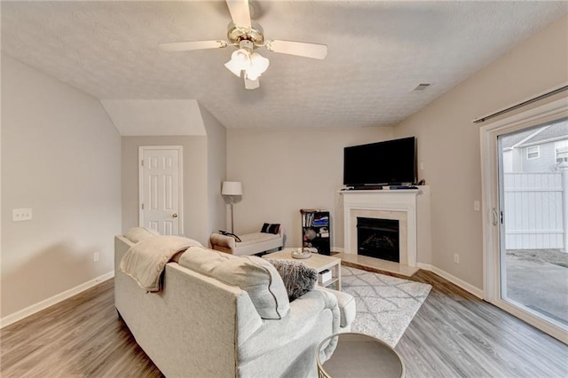 living room featuring light hardwood / wood-style floors, ceiling fan, and a textured ceiling