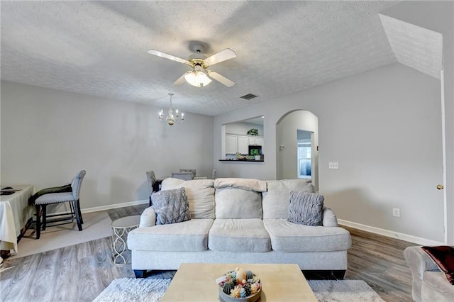 living room with a textured ceiling, ceiling fan with notable chandelier, lofted ceiling, and hardwood / wood-style floors