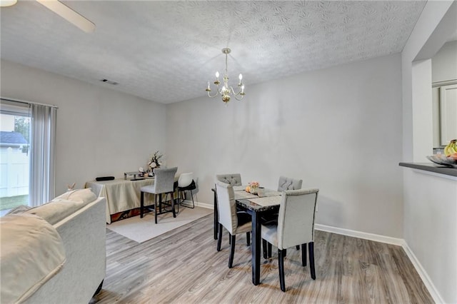 dining room featuring an inviting chandelier, light hardwood / wood-style floors, and a textured ceiling