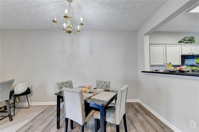 dining room with a textured ceiling, light hardwood / wood-style flooring, and a notable chandelier