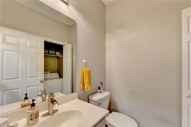 bathroom featuring vanity, toilet, and washer / dryer