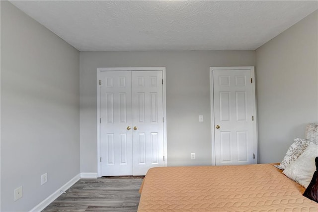 bedroom featuring a closet, a textured ceiling, and dark wood-type flooring