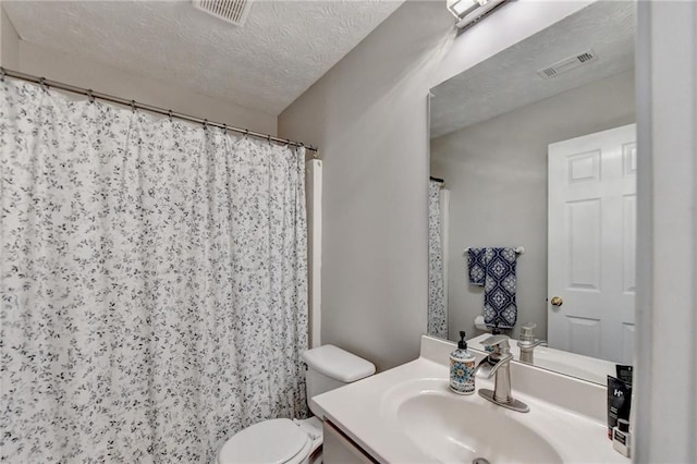 bathroom with a shower with curtain, vanity, toilet, and a textured ceiling