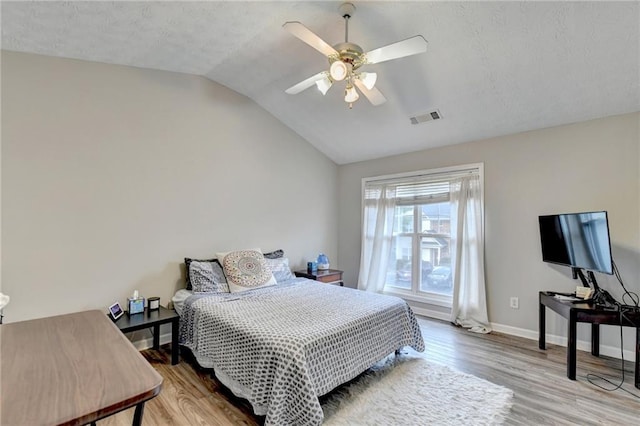 bedroom featuring ceiling fan, a textured ceiling, light wood-type flooring, and vaulted ceiling