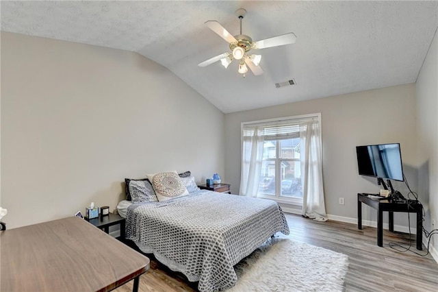 bedroom featuring ceiling fan, a textured ceiling, light wood-type flooring, and vaulted ceiling