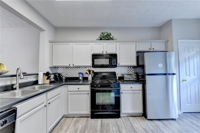 kitchen with light wood-type flooring, black appliances, white cabinetry, and sink