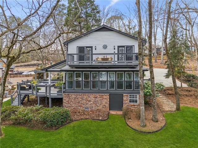 rear view of house featuring brick siding, a sunroom, a yard, crawl space, and a wooden deck