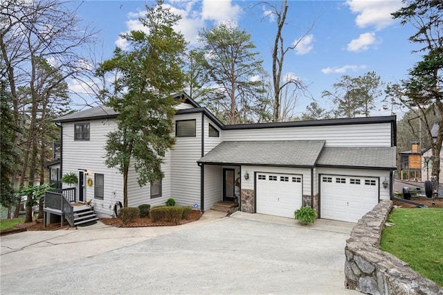 view of front of home with driveway, a shingled roof, and a garage