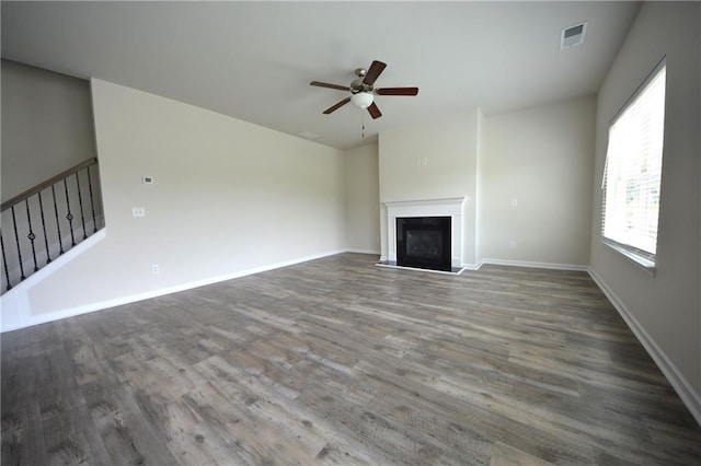 7753 Hansel Ln, Lithonia, GA 30058 - unfurnished living room with a ceiling fan, a fireplace with raised hearth, wood finished floors, and stairs