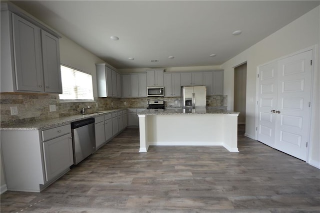 7753 Hansel Ln, Lithonia, GA 30058 - kitchen with stainless steel appliances, gray cabinets, decorative backsplash, light stone countertops, and wood finished floors