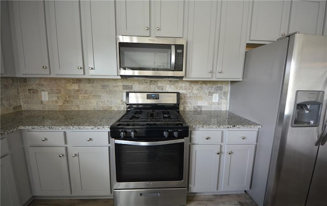 7753 Hansel Ln, Lithonia, GA 30058 - kitchen with appliances with stainless steel finishes, tasteful backsplash, and light stone counters