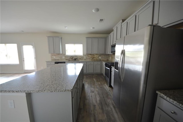 7753 Hansel Ln, Lithonia, GA 30058 - kitchen featuring stainless steel appliances, a center island, dark wood-style flooring, gray cabinetry, and tasteful backsplash