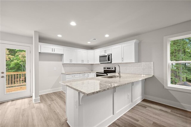 kitchen featuring white cabinetry, sink, tasteful backsplash, light stone counters, and appliances with stainless steel finishes