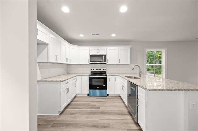 kitchen featuring white cabinets, appliances with stainless steel finishes, kitchen peninsula, and sink