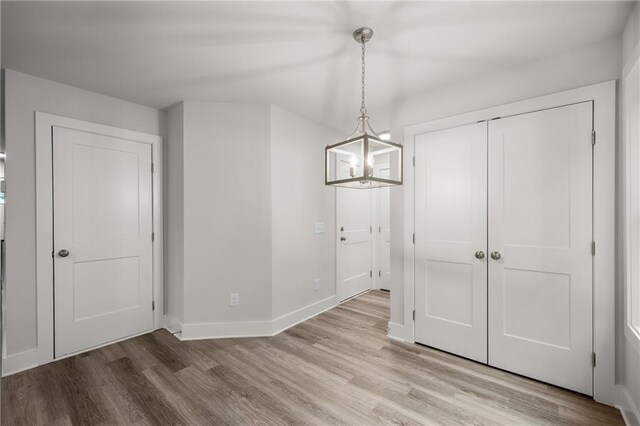 unfurnished dining area featuring a notable chandelier and light wood-type flooring