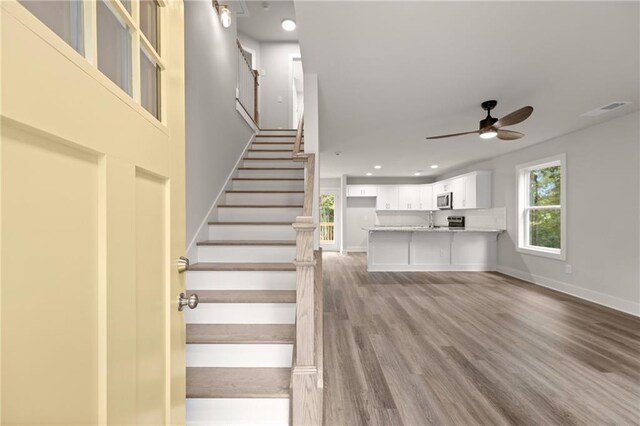 stairway with wood-type flooring, ceiling fan, and sink