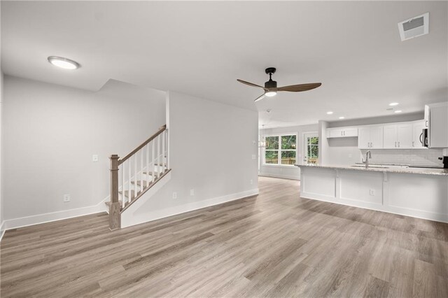 unfurnished living room featuring ceiling fan, sink, and light hardwood / wood-style flooring