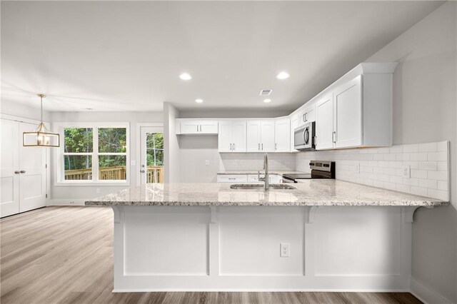 kitchen featuring white cabinetry, sink, stainless steel appliances, kitchen peninsula, and decorative light fixtures