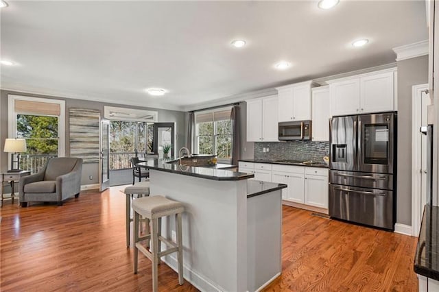 1604 Gilstrap Ln NW, Atlanta, GA 30318 - kitchen with stainless steel appliances, ornamental molding, dark countertops, wood finished floors, and white cabinets