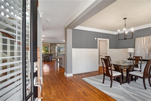 1604 Gilstrap Ln NW, Atlanta, GA 30318 - dining area with wood finished floors, a chandelier, a wainscoted wall, crown molding, and a decorative wall