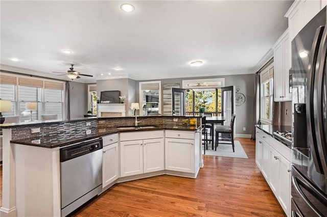 1604 Gilstrap Ln NW, Atlanta, GA 30318 - kitchen featuring stainless steel appliances, a ceiling fan, light wood-style flooring, white cabinetry, and ornamental molding