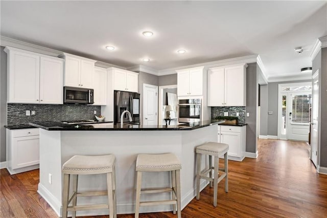 1604 Gilstrap Ln NW, Atlanta, GA 30318 - kitchen featuring appliances with stainless steel finishes, a kitchen breakfast bar, backsplash, white cabinetry, and crown molding