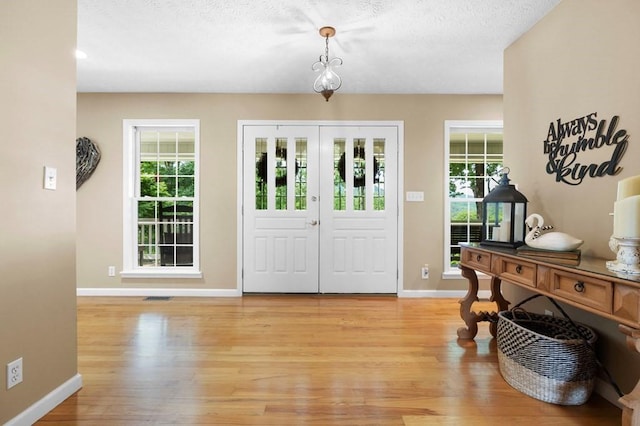 foyer featuring a healthy amount of sunlight, light hardwood / wood-style flooring, and a textured ceiling