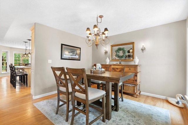 dining room with light wood-type flooring and an inviting chandelier