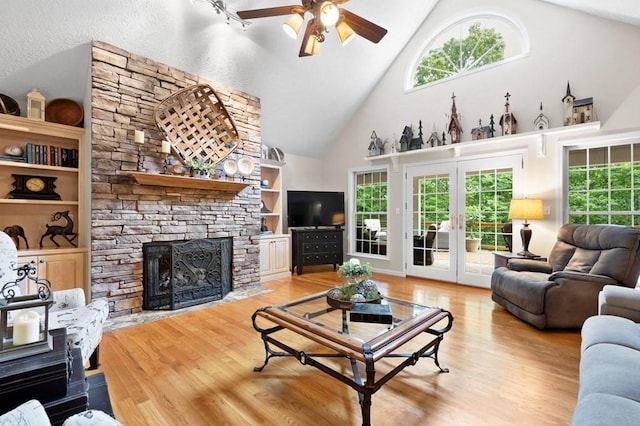 living room featuring built in shelves, french doors, plenty of natural light, and light hardwood / wood-style floors