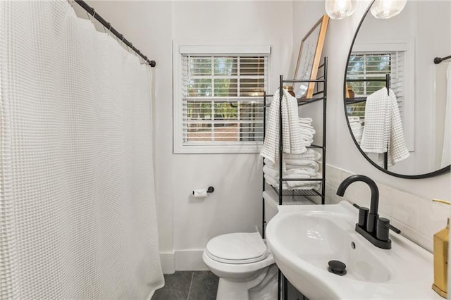 full bathroom featuring a sink, toilet, a shower with shower curtain, and a wealth of natural light