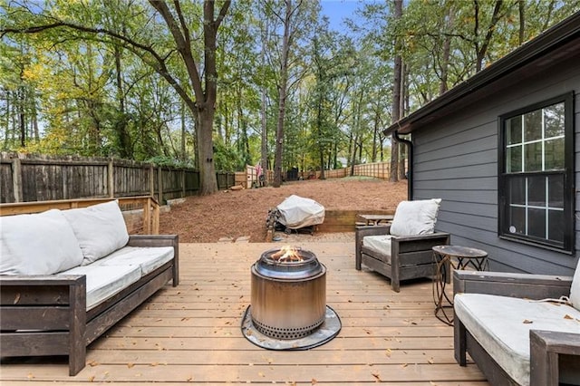 wooden terrace with an outdoor living space with a fire pit and a fenced backyard