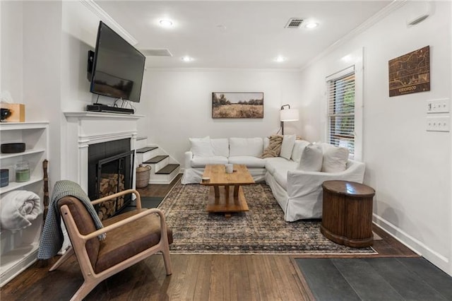 living room with visible vents, crown molding, baseboards, hardwood / wood-style floors, and a fireplace