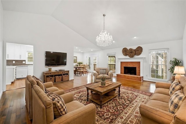 living area featuring a brick fireplace, a chandelier, recessed lighting, wood finished floors, and high vaulted ceiling