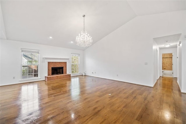unfurnished living room featuring a chandelier, wood finished floors, a fireplace, and baseboards